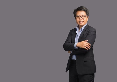 Portrait of a businesswoman with short black hair in a suit while standing with arms crossed on a gray background photo