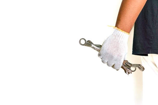 a person holding a wrench in one hand and a pair of gloves in the other photo
