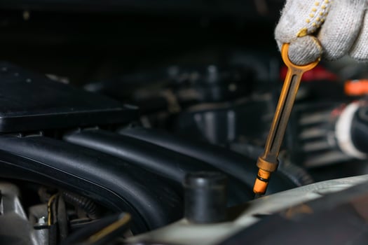 A mechanic checks oil levels using a dipstick in a car engine compartment. photo