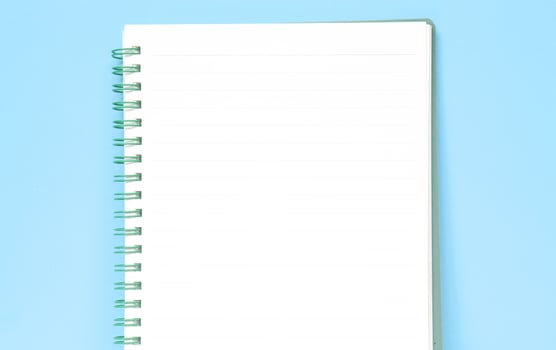 Top view of blank note paper isolated on blue background with copy space. Back to school and education concept, a journaling book photo