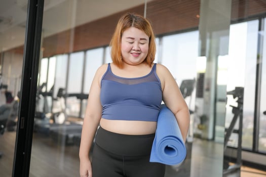 obese asian woman with blue yoga mat in gym photo