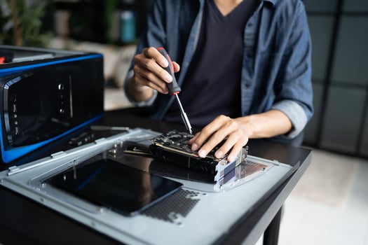 Engineer is working on a computer with a screwdriver in room photo