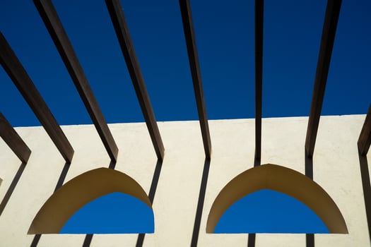 two Arabic windows on a yellow wall with crossbars instead of a roof photo