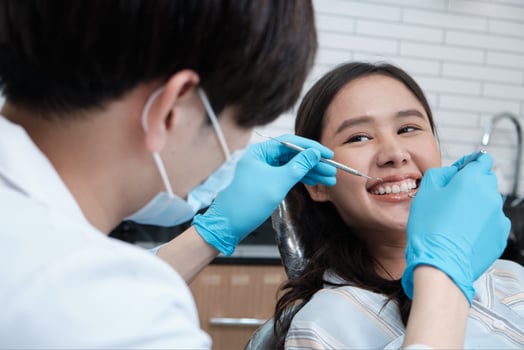 Asian male dentist examines beautiful young female patient's teeth stomatology in dental clinic, well-being hygiene checks, and professional orthodontic healthcare work in doctor's office hospital. photo
