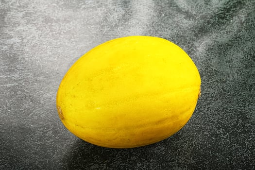 A yellow melon on a black surface photo