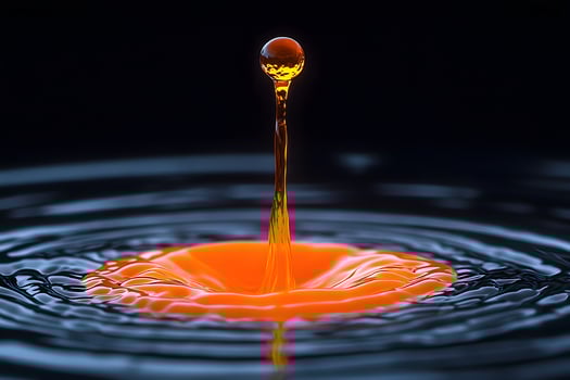 Vivid Orange Water Droplet Splash on Dark Reflective Surface for Abstract Art and Design Concepts photo