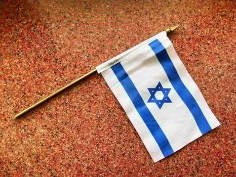 Israeli flag resting on speckled surface with golden pole photo
