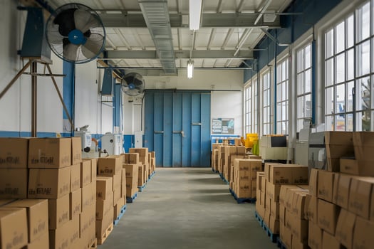 Industrial storage room with boxes, blue door, fans, and well lit interior photo