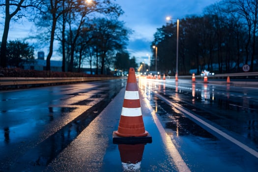 Orange cone on twilights wet road reflects lights, signaling roadside repairs photo