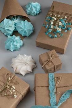 Box gifts in brown kraft paper with flowers, marshmallow merengue blue for congratulations, vertical photo