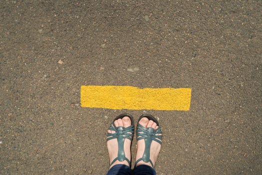 Pair of sandaled feet standing on asphalt road with yellow line. photo