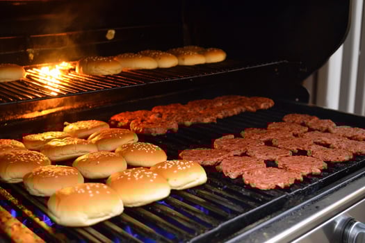 A grill with hamburgers and buns cooking on it photo
