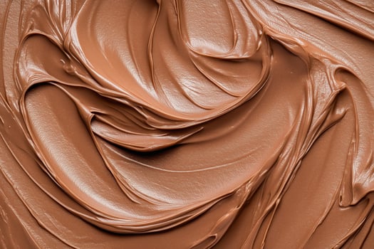 Close-up of creamy mocha or chocolate mousse smooth texture with elegant wave-like patterns. Rich texture of the dessert. Mocha mousse, color of the year. Background photo