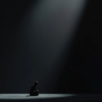 Solitary figure in a dark space illuminated by a focused light beam photo