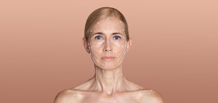 A woman stands against a soft, neutral background while focusing on her skin care routine. Her expression is serene as she engages in a pampering ritual dedicated to enhancing her beauty. photo