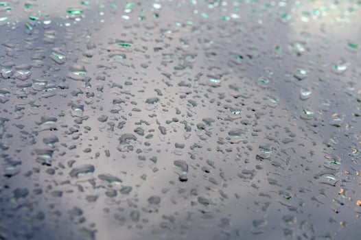Droplets cascade across a reflective surface during a tranquil rain shower in the early morning light photo