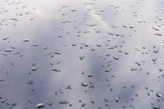 Raindrops dance on a reflective surface during a quiet afternoon in an urban setting photo