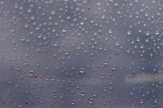Raindrops create a mesmerizing pattern on a windowpane, reflecting the beauty of a cloudy afternoon photo