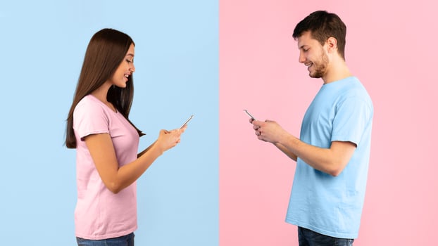 People, Technology And Communication Concept. Side view portrait of woman and man texting on mobile phone, isolated over blue and yellow studio background. Smiling couple chatting in social media photo