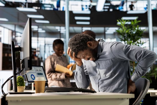 Black enterprise worker takes a break and stretches his back muscles, dealing with a spinal spasm and headache. Male office employee trying to relieve pain and correct his position. photo
