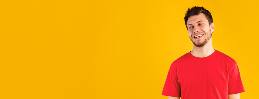 Place For Advert. Headshot portrait of smiling guy standing and looking away at copy space. Young man posing isolated over blue studio background wall. Banner for promotion, panorama. photo
