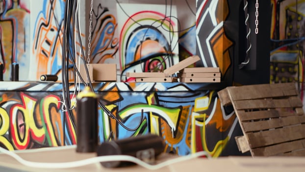 Close up shot of electric cables hanging in trashed desolate building with graffiti drawings on walls. Spraying paint cans in underground criminal den used as headquarters by teenagers photo