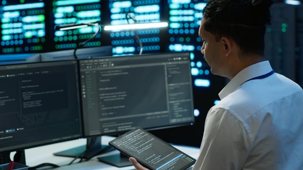 System administrator in data center installing software on computer, troubleshooting issues using tablet. IT staff member in server hub establishing performance benchmarks, camera A photo