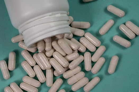 bottle of pills, some of which spilled onto a light blue photo