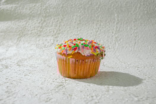 a cupcake with sprinkles on white texture background photo