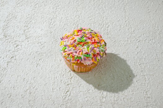 a cupcake with sprinkles on top of a white wall photo