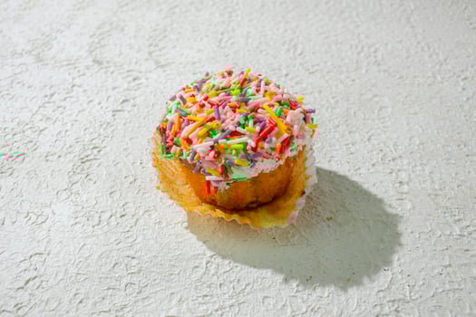 a cupcake with sprinkles on top of a white surface photo