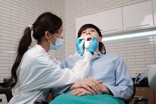 Asian female dentist examines male patient teeth and toothache stomatology in dental clinic, well-being hygiene checks, and professional orthodontic healthcare work in doctor's office hospital. photo
