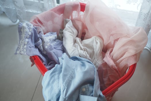 Colorful laundry in a red basket by a window brightens the space photo