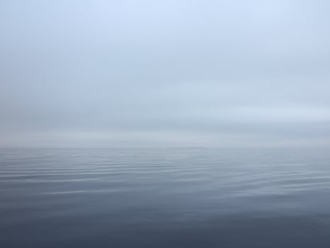 thick white fog fell on the sea, calm and silence, the water merges with the sky photo