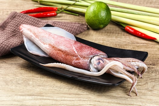 A squid on a plate with a knife and some other vegetables photo