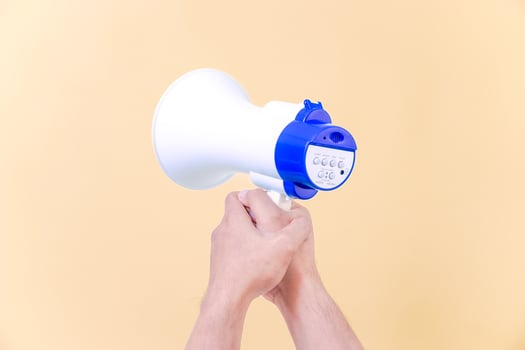 a person holding a megaphone over a beige background photo