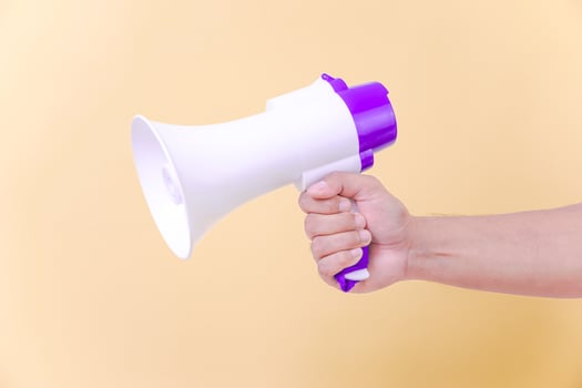 a person holding a megaphone isolated againts beige background photo