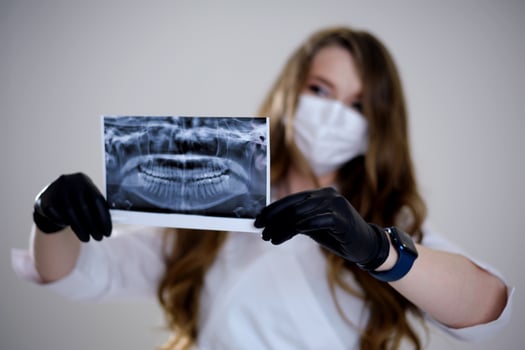 A dental professional wearing gloves points to a dental X-ray displayed on a monitor, highlighting details of a patient's teeth for review or diagnosis. photo