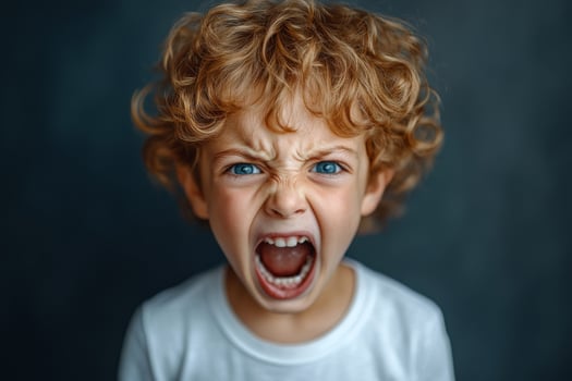 Close-up of furious preschool child with blue eyes and curly red hair shouting with opened mouth on dark background photo