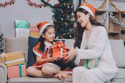 Merry Christmas and Happy Holidays. Cheerful mom and her cute daughter girl exchanging gifts. Parent and little child having fun near tree photo