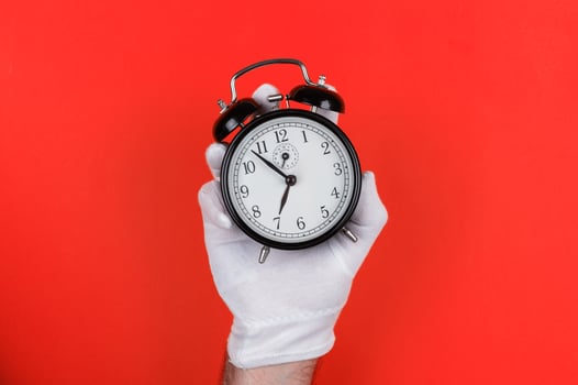 Gloved Hand Holding Black Alarm Clock on Red photo