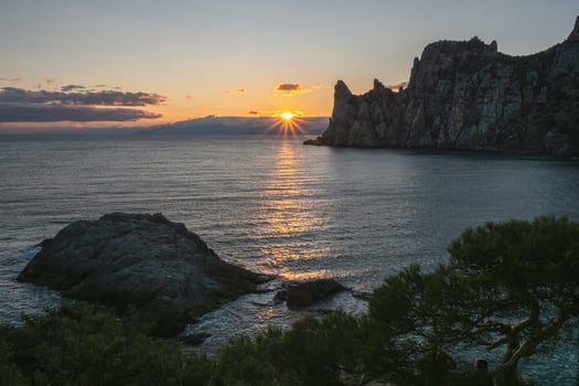 Last rays of the setting sun on the horizon near a cliff. photo