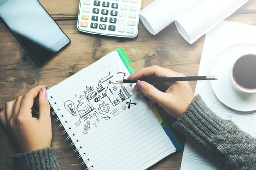 Woman's hand writing on notebook with business ideas photo