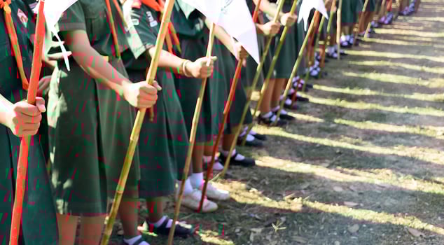 A group of children wearing green uniforms holding flags photo