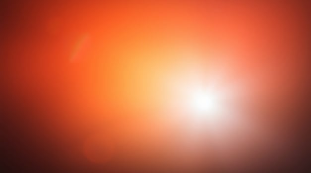 A bright orange light is shining through a dark background photo