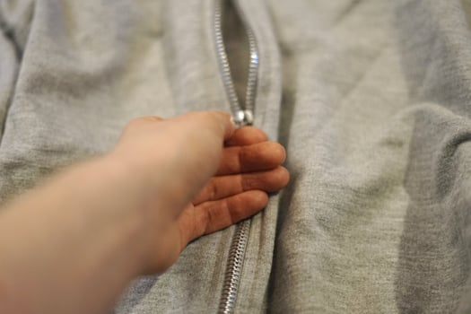 woman hand unzipping grey jacket with silver zip lock winter cold warm clothes open close photo
