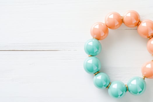Colorful mint and peach bead bracelet resting on a light wooden surface in a bright and airy setting photo