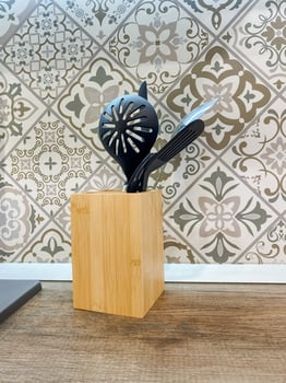 This is a beautifully crafted wooden utensil holder, containing sleek black utensils arranged neatly within it, showcasing a perfect blend of natural materials and artistic design photo