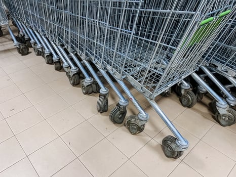 A long and orderly row of shopping carts is perfectly lined up on a clean, tiled floor within the store, ready for customers to easily grab and use for their shopping needs photo