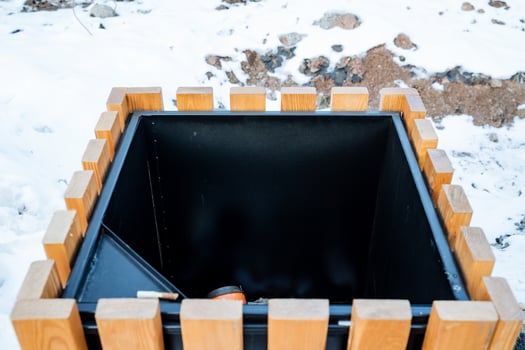 A wooden trash can is presently resting in the soft snow, surrounded by the stunningly beautiful winter landscape, creating a picturesque scene of natures serene beauty in cold weather photo